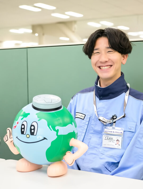 ほほ笑む小泉柊太さんと下水道局のキャラクター「アースくん」の写真。